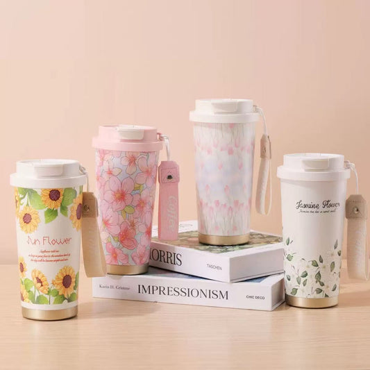 Set of four floral-themed tumblers on a beige surface with books in the background